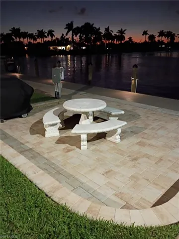 Surrounding community with a water view, a boat dock, and a patio area