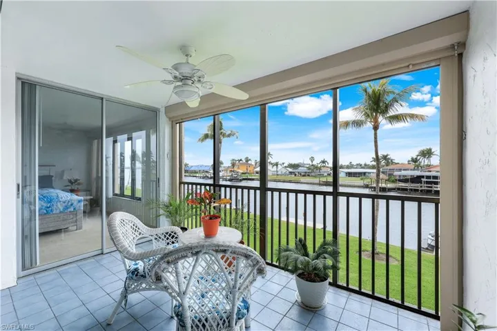 Sunroom with a water view, ceiling fan, and tile patterned floors