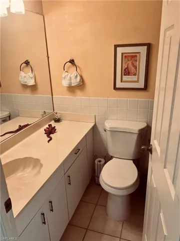 Bathroom with toilet, tile patterned flooring, vanity, tasteful backsplash, and tile walls