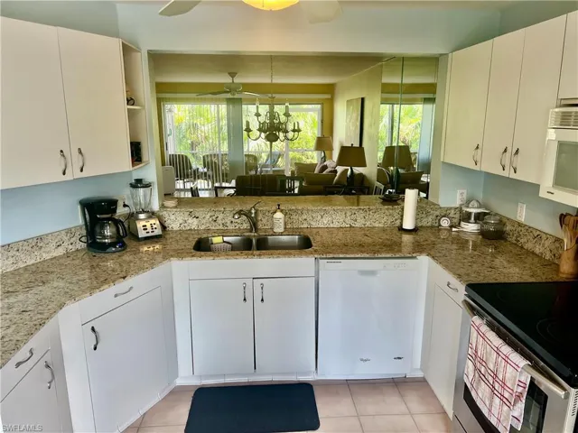 Kitchen featuring ceiling fan with notable chandelier, white appliances, white cabinetry, and light stone countertops