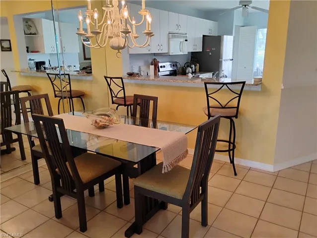Tiled dining area with ceiling fan with notable chandelier