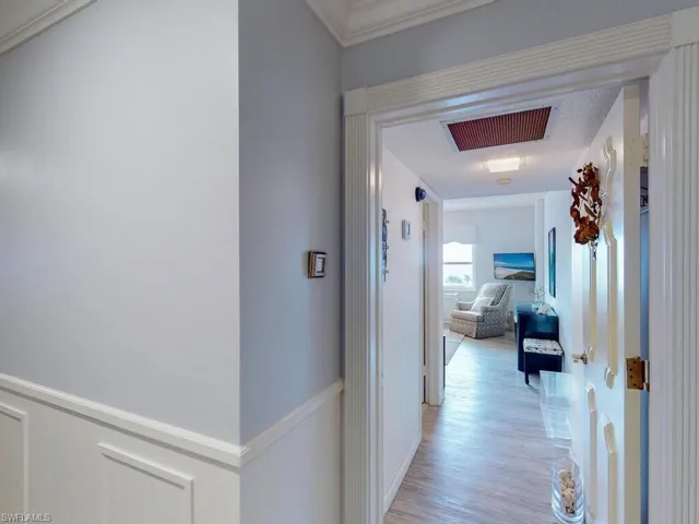 Corridor with crown molding, a textured ceiling, and light wood-type flooring