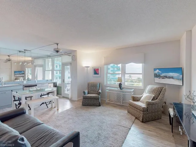 Living room featuring a textured ceiling, light hardwood / wood-style floors, and ceiling fan