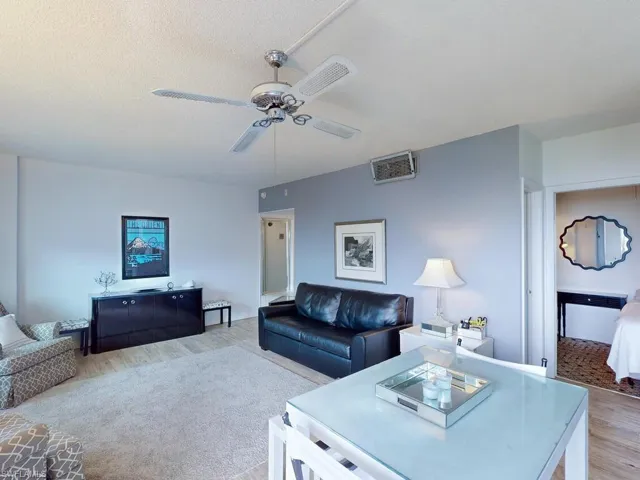 Living room featuring ceiling fan, a textured ceiling, and light wood-type flooring