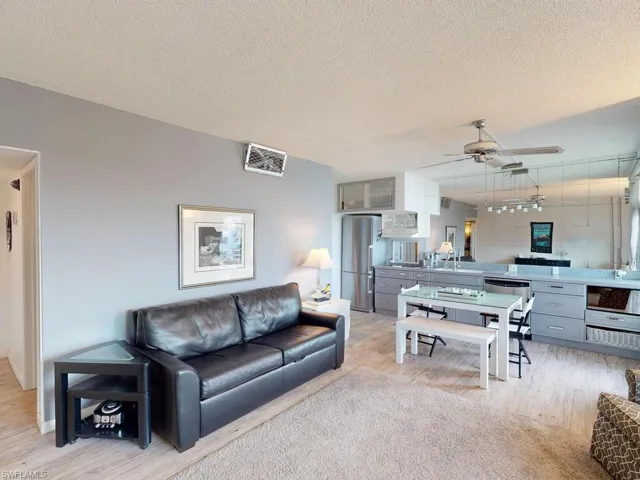 Living room featuring ceiling fan, sink, a textured ceiling, and light hardwood / wood-style flooring