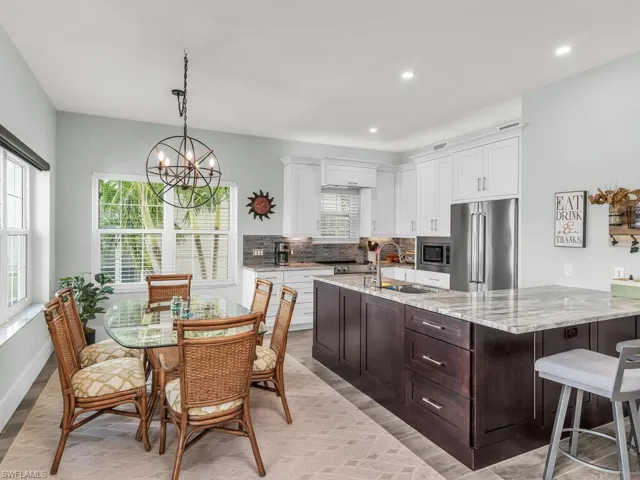 Kitchen featuring white cabinets, light stone countertops, stainless steel appliances, and a chandelier