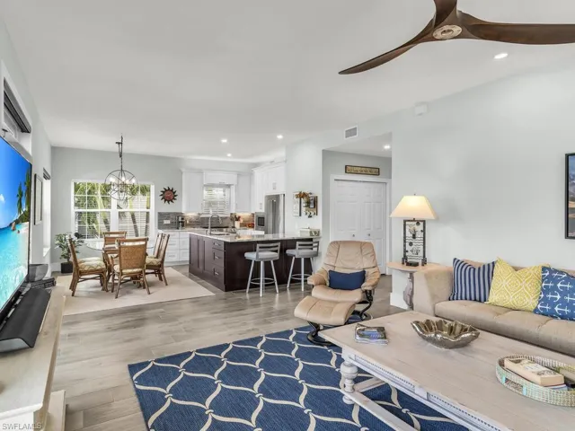 Living room featuring ceiling fan with notable chandelier, light hardwood / wood-style flooring, and sink
