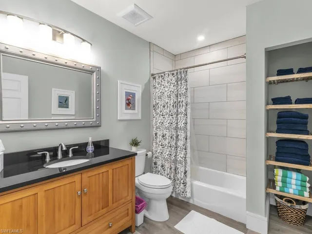 Full bathroom featuring toilet, hardwood / wood-style floors, vanity, and shower / tub combo with curtain