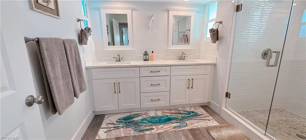 Bathroom featuring double vanity, a shower stall, baseboards, and a sink