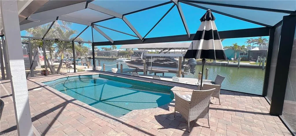View of pool with a lanai, a dock, a water view, and boat lift
