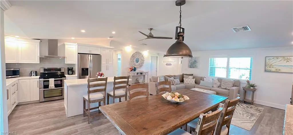 Dining room featuring visible vents, light wood-type flooring, a ceiling fan, and vaulted ceiling