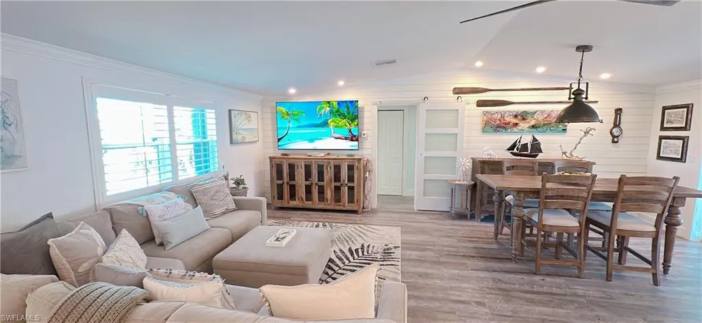 Living room featuring vaulted ceiling, visible vents, crown molding, and wood finished floors