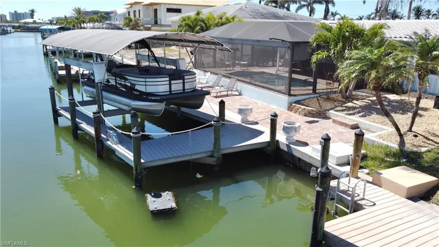 Dock area with a water view, a swimming pool, a lanai, a patio, and boat lift