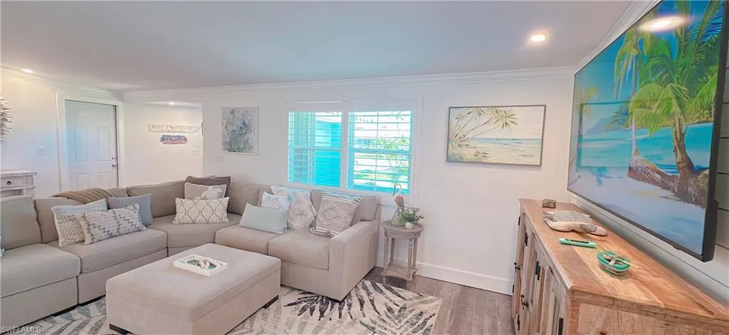 Living room with light wood-type flooring, crown molding, and baseboards