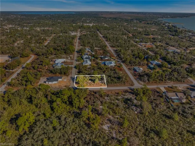 View of property location featuring a nearby body of water, nearby suburban area, and property parcel outlined