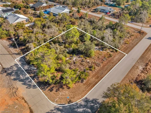 Aerial perspective of suburban area featuring property boundaries highlighted and a tree filled landscape