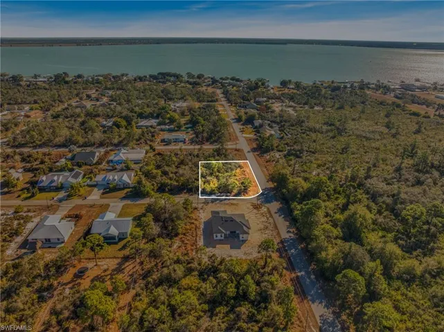 Aerial perspective of suburban area with property boundaries highlighted and a nearby body of water
