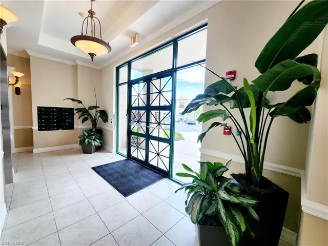 Entrance foyer with mail area, a tray ceiling, tile patterned floors, and crown molding