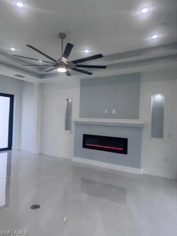 Unfurnished living room with a glass covered fireplace, recessed lighting, ceiling fan, and baseboards