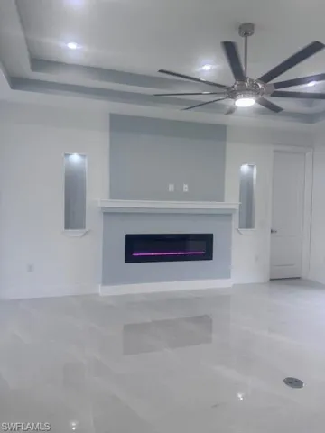 Unfurnished living room with a glass covered fireplace, ceiling fan, baseboards, and recessed lighting