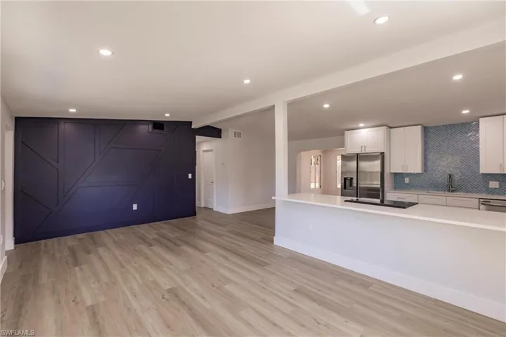 Kitchen with light hardwood / wood-style floors, backsplash, stainless steel fridge with ice dispenser, sink, and white cabinetry