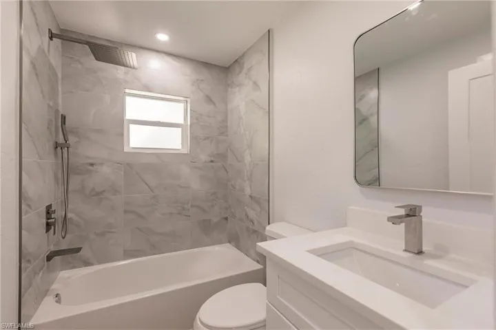 Full bathroom with tiled shower / bath combo, vanity, and toilet