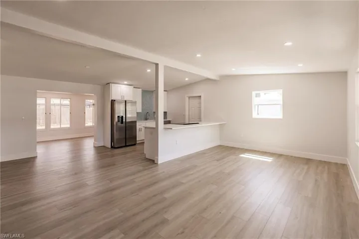 Unfurnished living room with sink, wood-type flooring, and vaulted ceiling with beams