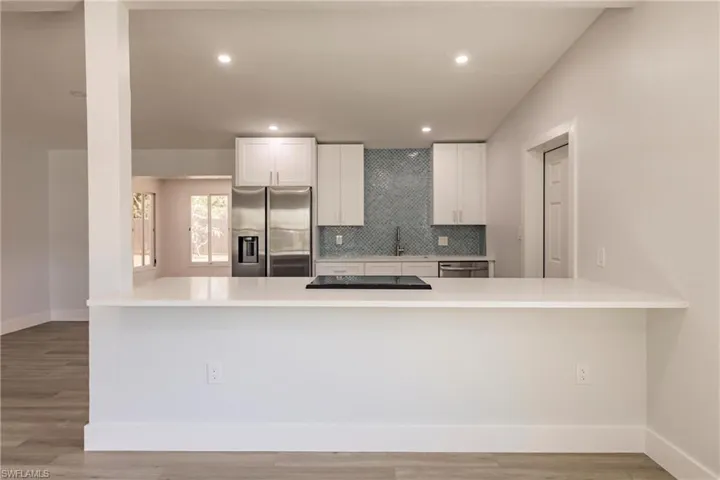 Kitchen featuring appliances with stainless steel finishes, white cabinets, backsplash, and wood-type flooring