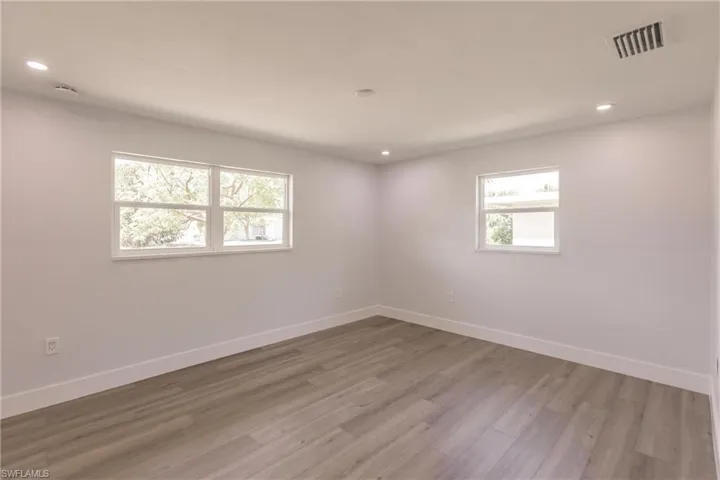 Empty room with a healthy amount of sunlight and hardwood / wood-style flooring