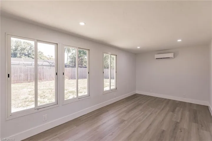 Unfurnished room featuring a wall unit AC and hardwood / wood-style flooring