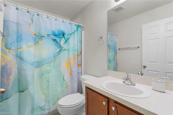 Guest bathroom featuring visible vents, toilet, curtained shower, and vanity