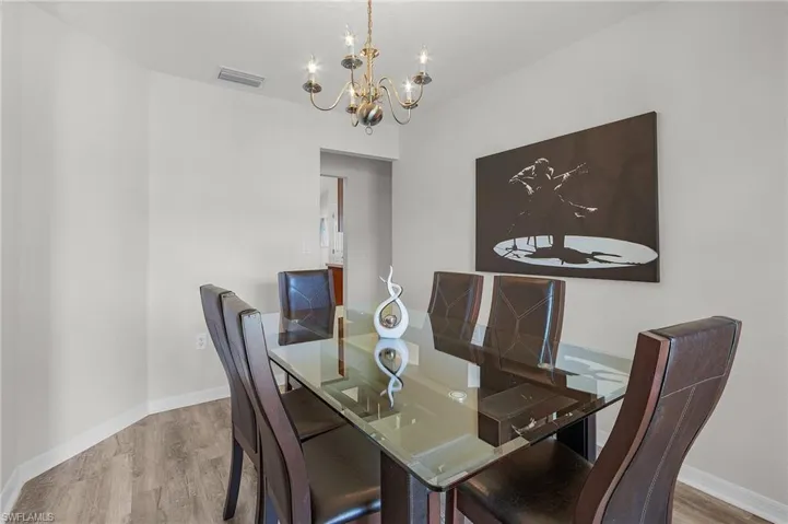 Dining space with a notable chandelier, visible vents, baseboards, and wood finished floors