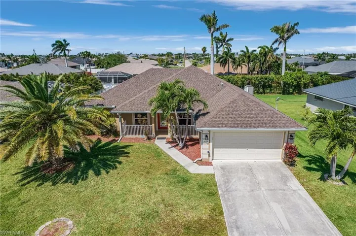Ranch-style house with a front yard, a shingled roof, a porch, a garage, and driveway