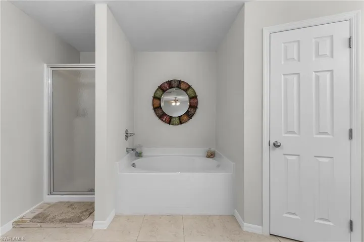 Full bath with a garden tub, baseboards, tile patterned flooring, and a stall shower