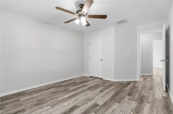 Unfurnished bedroom with baseboards, wood finished floors, visible vents, and ceiling fan