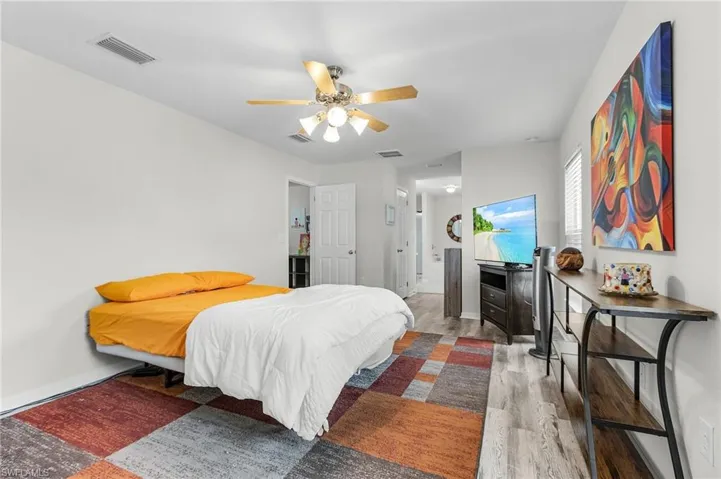 Bedroom featuring ceiling fan, baseboards, wood finished floors, and visible vents