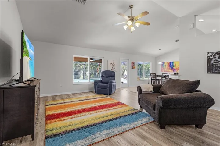 Living area featuring wood finished floors, vaulted ceiling, and a ceiling fan