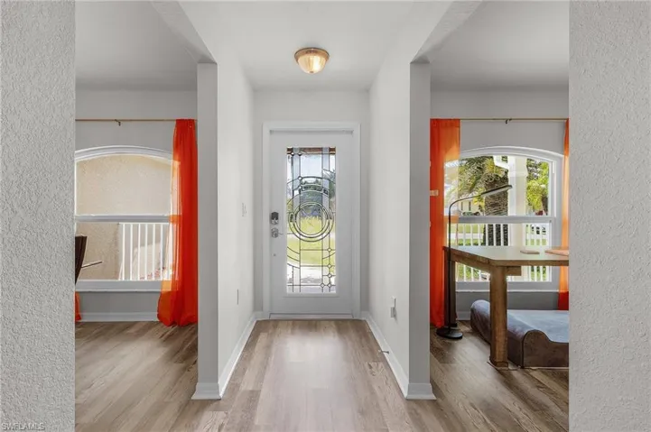 Foyer featuring a textured wall, baseboards, and wood finished floors