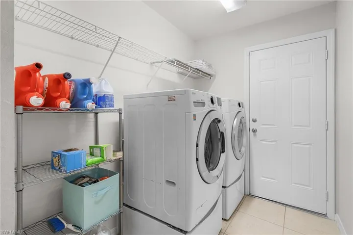 Laundry room featuring independent washer and dryer, light tile patterned flooring, and laundry area