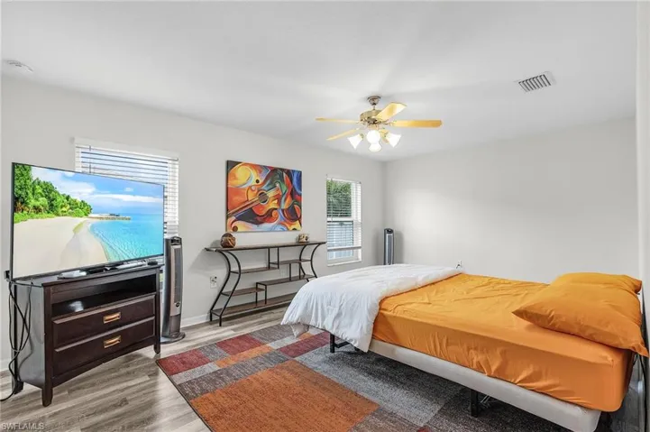 Bedroom with wood finished floors, visible vents, and ceiling fan