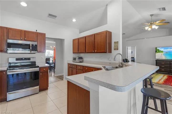 Kitchen with a kitchen bar, visible vents, light countertops, a sink, and stainless steel appliances