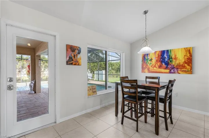 Dining space featuring light tile patterned floors, vaulted ceiling, and baseboards