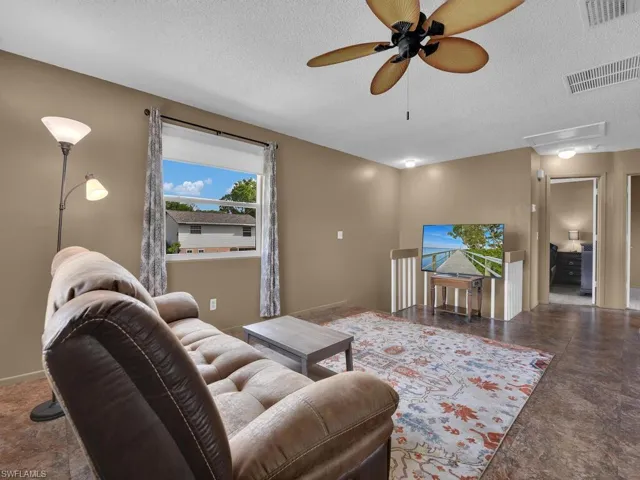 Living room with a textured ceiling and a ceiling fan