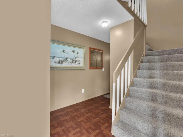 Stairs with a textured ceiling and baseboards