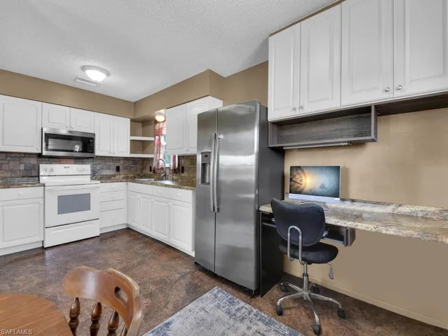 Kitchen with stainless steel appliances, a sink, open shelves, tasteful backsplash, and a textured ceiling