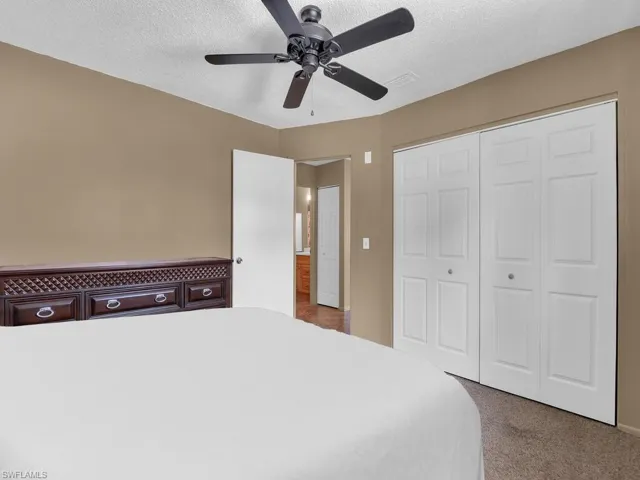 Unfurnished bedroom featuring carpet floors, a closet, ceiling fan, and a textured ceiling