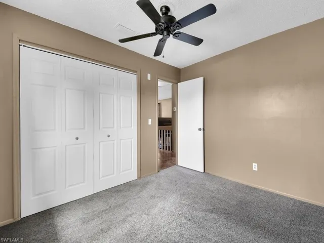 Unfurnished bedroom featuring carpet floors, a closet, a ceiling fan, and a textured ceiling