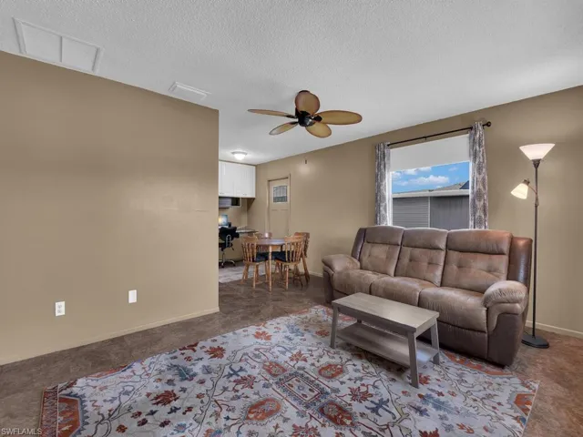 Living room featuring a ceiling fan, a textured ceiling, and baseboards