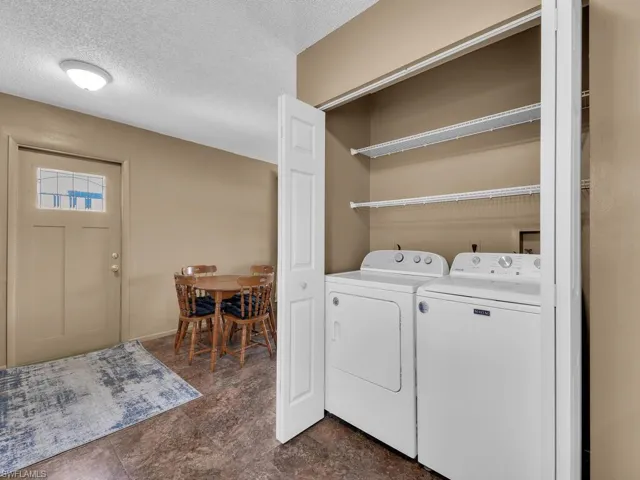 Laundry room featuring separate washer and dryer and a textured ceiling