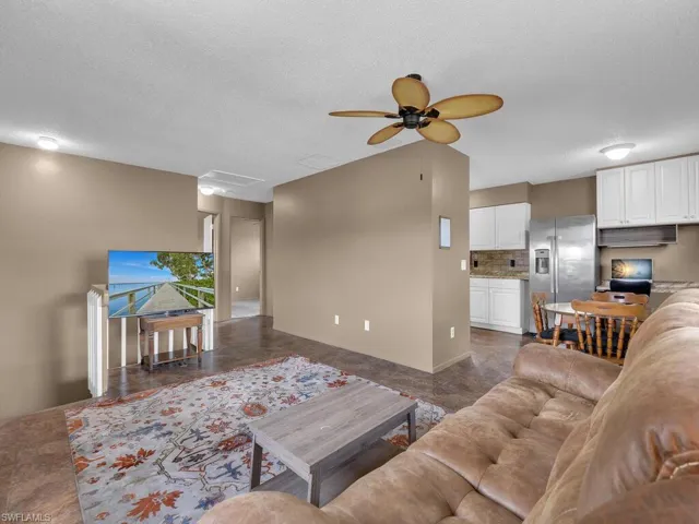 Living room featuring a ceiling fan, a textured ceiling, and baseboards